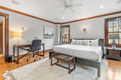 Cozy bedroom featuring a bed, desk, and soft area rug in a well-lit space.