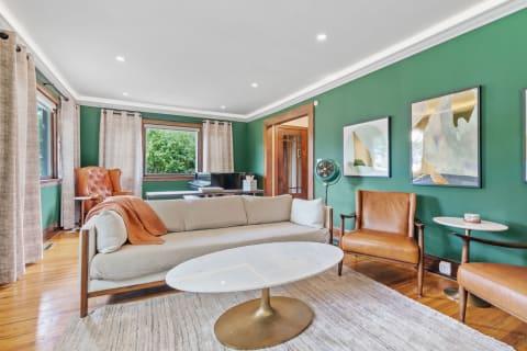 Cozy living room featuring green walls, a light sofa, and a marble coffee table.