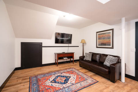 A cozy living room with a leather sofa, colorful rug, and a television set.