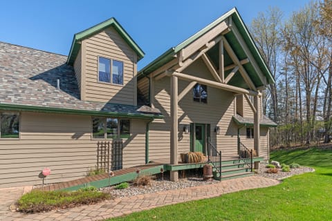 A contemporary rustic home featuring brown siding, green accents, and a well-kept garden.