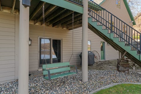 Outdoor area with a hanging green swing, pebbles, and an elevated deck.