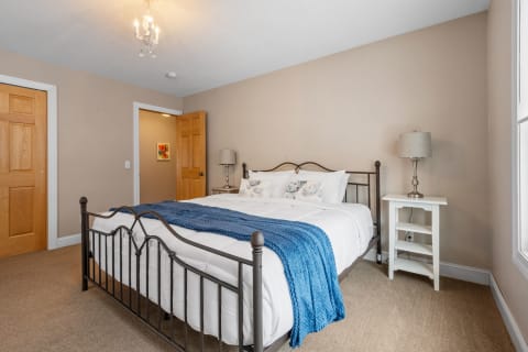 A cozy bedroom featuring a metal bed frame, decorative pillows, and a blue throw blanket.