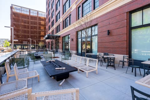 Modern urban patio with contemporary seating, fire features, and brick architecture.