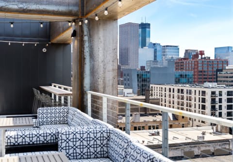 Private balcony with stylish seating and city views, featuring string lights.