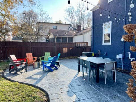 Cozy outdoor patio with colorful chairs and dining table under string lights.