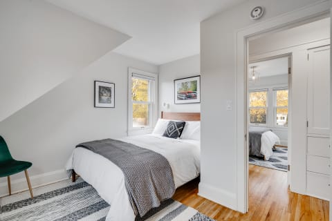 Cozy bedroom with a double bed, green chair, and natural light from large windows.