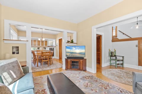 A bright living room with a sofa, television, and dining area, showcasing a warm atmosphere and artistic elements.