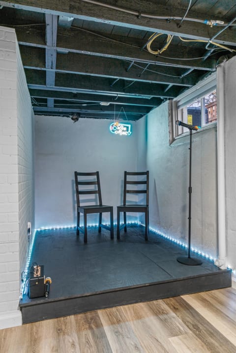 An intimate live music stage featuring two black chairs and a microphone.