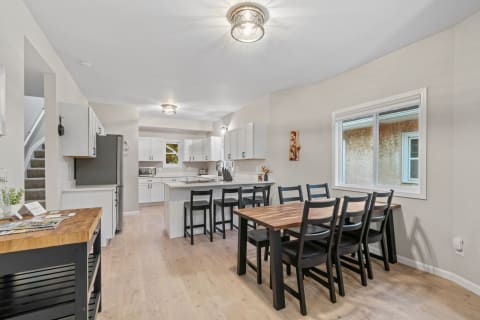 A bright and modern kitchen with a dining area, wooden table, and contemporary design elements.