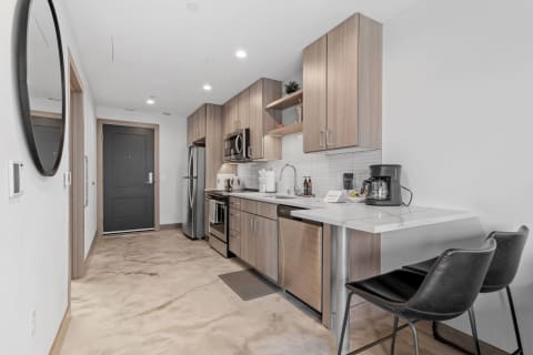 Stylish kitchen with light wood cabinets, stainless steel appliances, and a black chair.