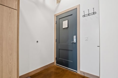 Entrance hallway featuring a dark blue door and simple wall hooks.