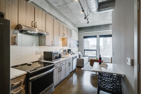 Contemporary kitchen with wooden cabinets, stainless steel appliances, and a cozy living area.