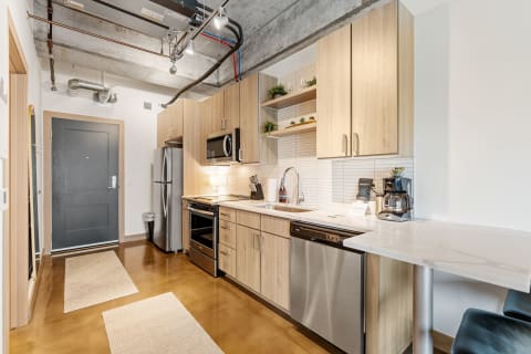 Modern kitchen with light wood cabinets and stainless steel appliances.