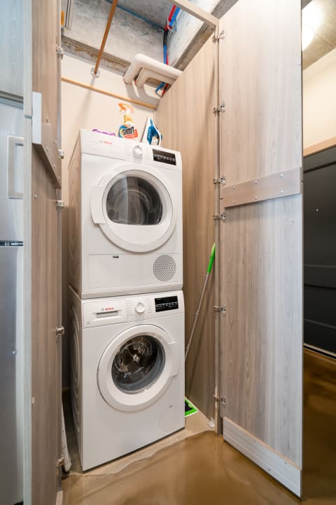 A compact laundry area featuring a white stacked washer and dryer against wooden panels.