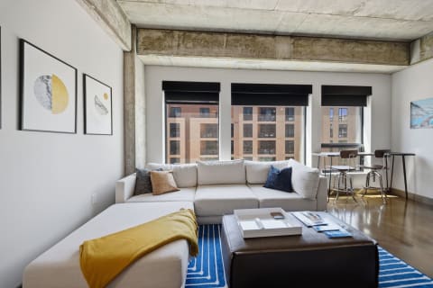 Cozy modern loft with a soft sectional sofa, concrete ceiling, and urban style decor.