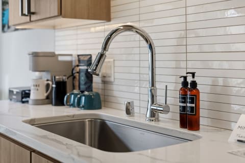Contemporary kitchen sink with a chrome faucet, marble countertop, and backdrop of white subway tiles.
