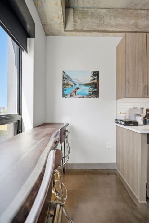 Modern kitchen featuring a wooden breakfast bar and nature-inspired artwork of a dog by a lake.