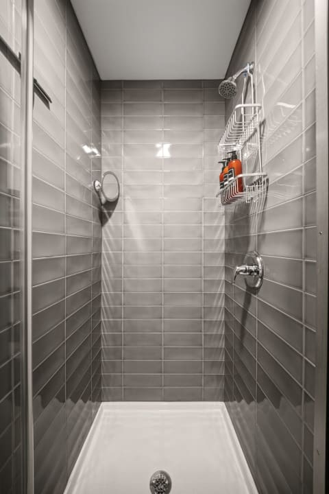 Interior view of a modern shower stall featuring gray tiles and shower accessories.