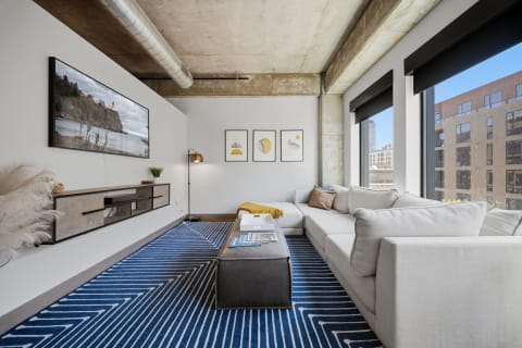 Stylish living room with a plush sectional sofa, framed artwork, and floor-to-ceiling windows overlooking the city.
