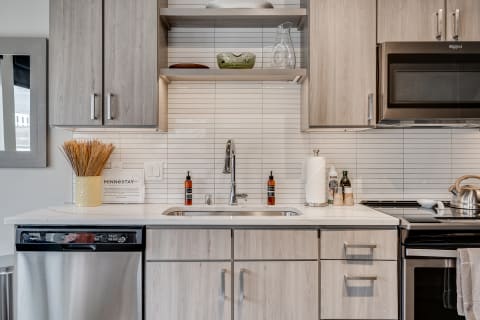 Modern kitchen with light wood cabinets and stainless steel appliances.