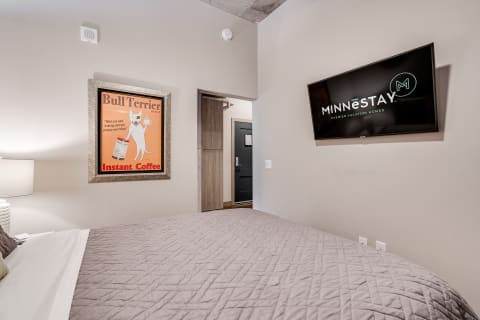 Modern bedroom interior featuring a vintage coffee poster and a wall-mounted TV.