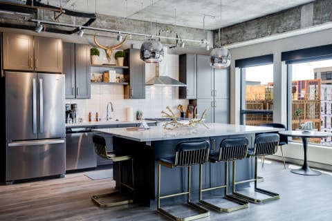 Contemporary kitchen with grey cabinets, white countertop, and stylish lighting.