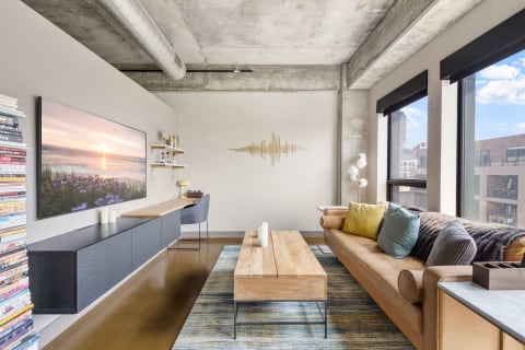 Modern living room with a leather sofa, wooden coffee table, and large windows.