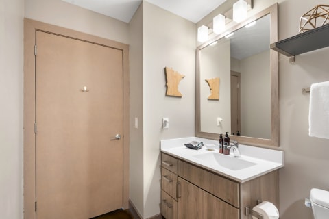 Modern bathroom with a double sink, decorative elements, and a beige door.