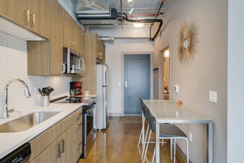 Modern kitchen with light wood cabinets and stainless steel appliances.