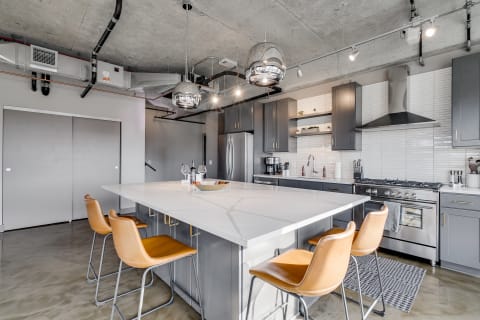 A contemporary kitchen featuring a large marble island and gray cabinetry.