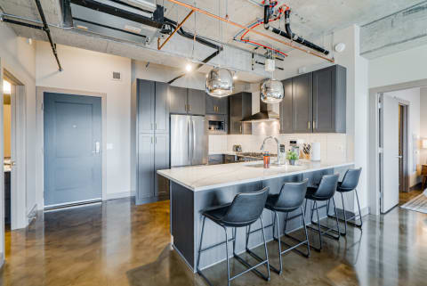 Modern kitchen with dark cabinets, marble island, and industrial accents.