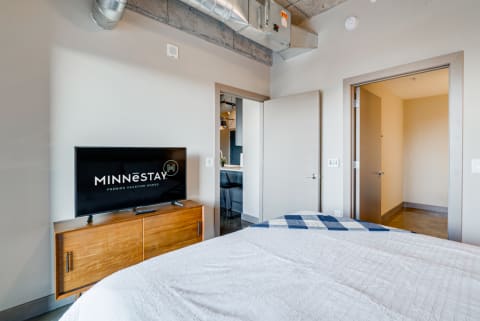 Modern bedroom featuring a wooden dresser with a flat-screen TV and contemporary design elements.