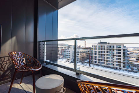 Balcony with modern chairs providing a view of city buildings under a clear sky.
