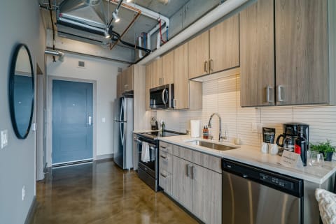 Modern kitchen interior with light wooden cabinets and stainless steel appliances.