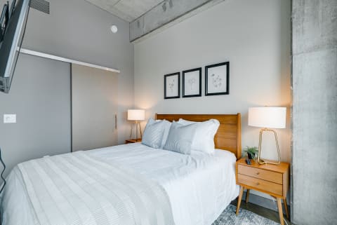 Modern bedroom with a wooden bed, decorative pillows, and framed artwork.