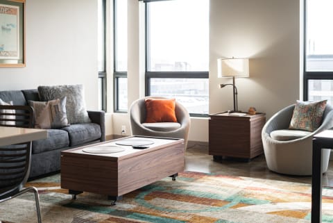 Modern living room with a gray sofa, armchairs, and a coffee table under bright windows.
