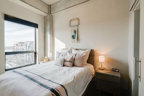 Cozy modern bedroom with large window and stylish decor.