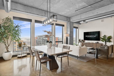 Modern living and dining room with large windows and contemporary furnishings.