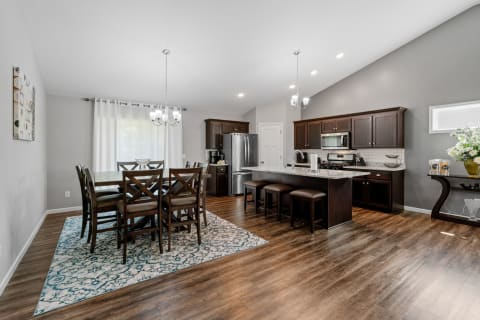 A stylish kitchen and dining area featuring dark wood furniture, granite countertops, and modern appliances.