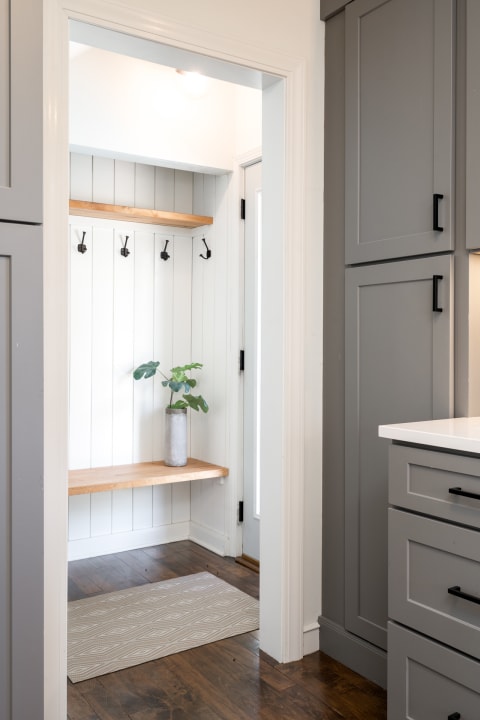 Modern mudroom entrance with a bench, hooks, and plant decor.