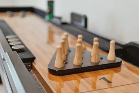 Pegs arranged on a shuffleboard table with metallic pucks in the background.