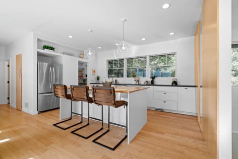 Modern kitchen with white cabinetry, large island, and natural light from windows.