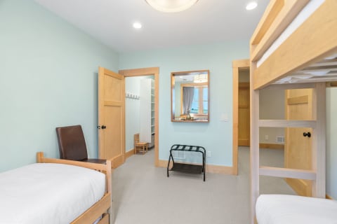 Interior view of a cozy bedroom with bunk beds, a chair, and a mirror.