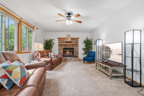 Inviting living room with leather couches, a fireplace, and bright windows.