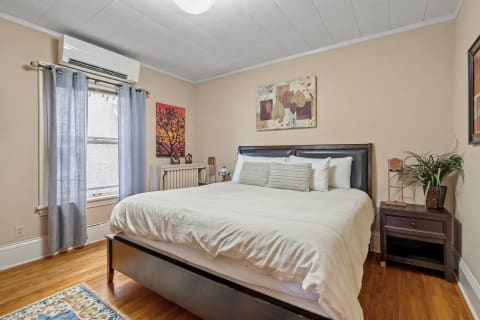 Cozy bedroom with a comfortable bed, decorative artwork, and natural light from a window.