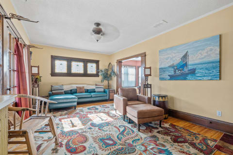 A living room with teal sofa, stained glass windows, and fishing-themed artwork.