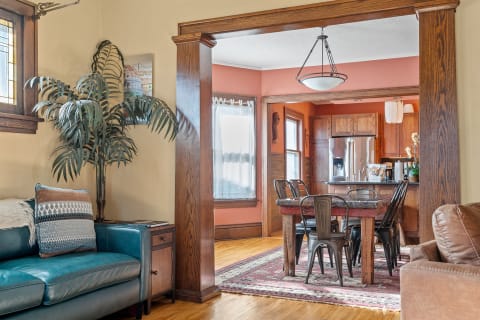 Open-concept living area featuring a teal sofa, wood accents, and a dining space with metal chairs.