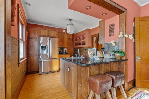 A modern kitchen with stainless steel appliances, wooden cabinetry, and a black granite countertop.