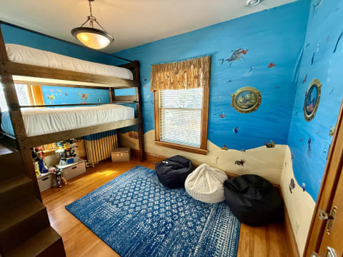 Children's bedroom featuring a lofted bunk bed and ocean-themed wall murals.