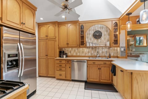 A modern kitchen featuring oak cabinets, stainless steel fridge, and stylish decor.